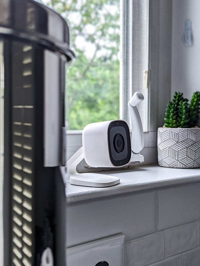 A sleek white security camera placed on a windowsill in a modern home setting, highlighting technology indoors.